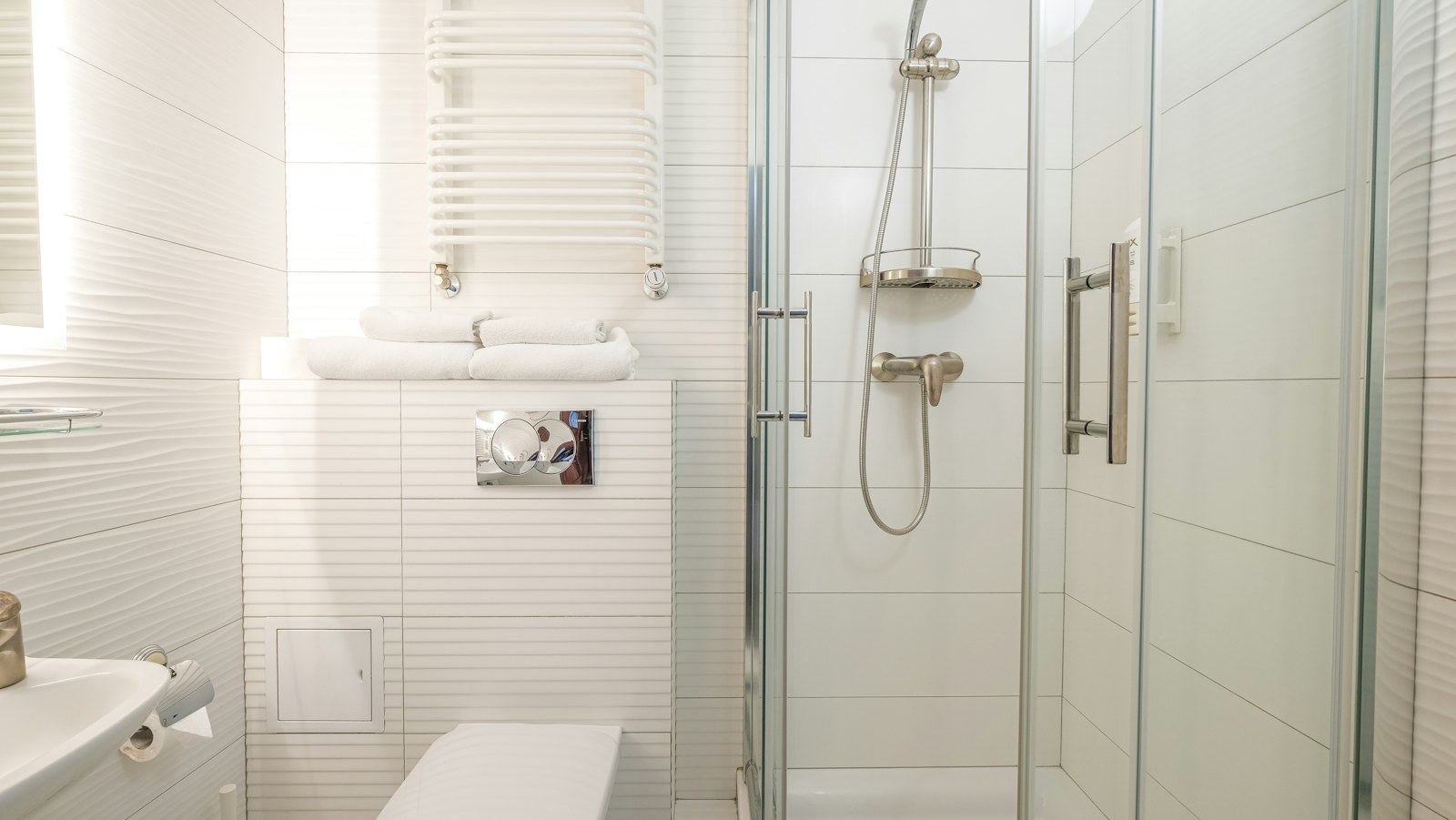 Clean glass shower screen and white tiled bathroom
