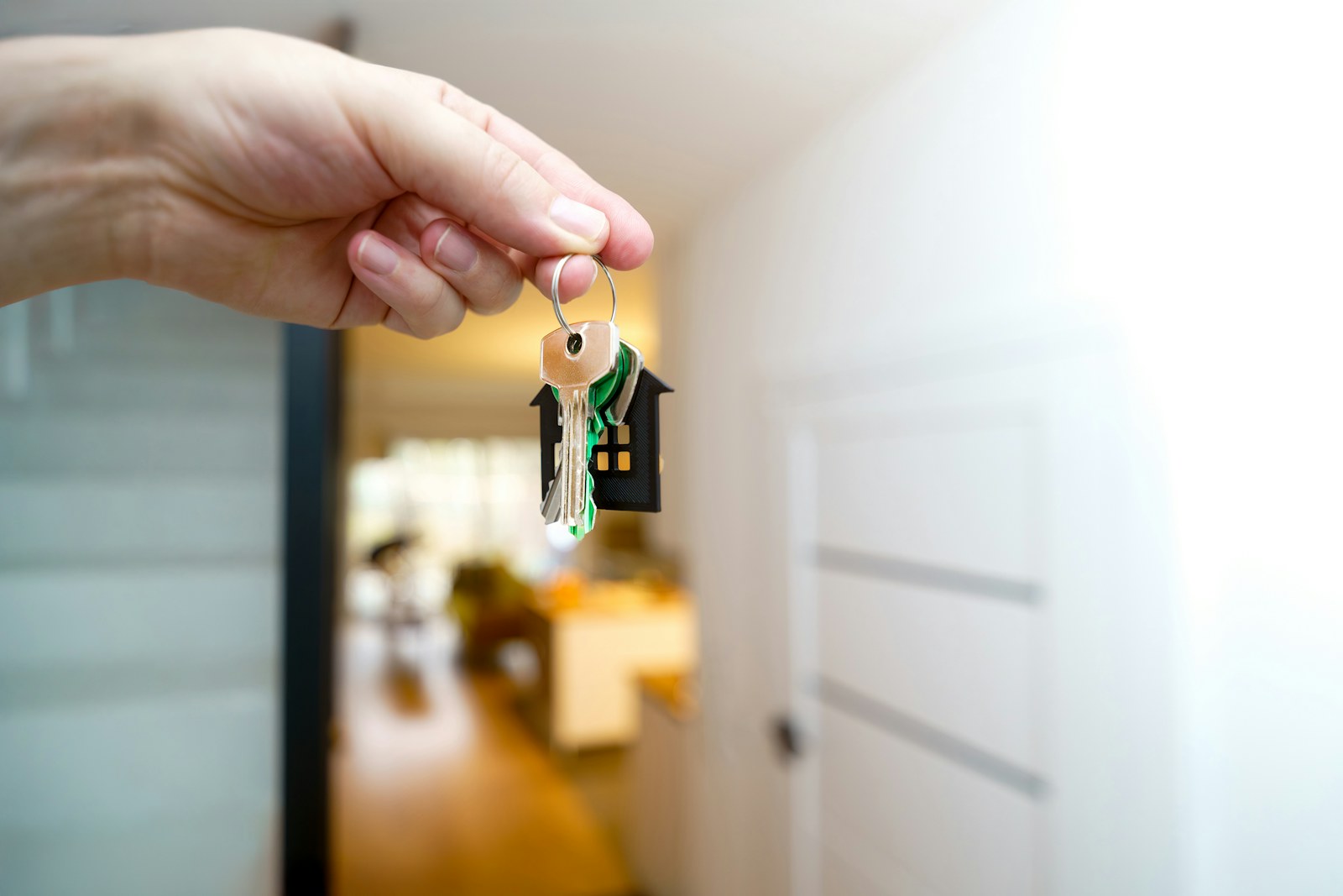 Hand holding house keys with a house-shaped keyring, ready for handover